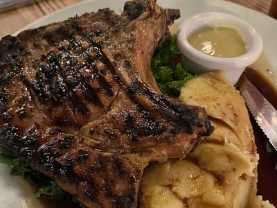 Grilled chops served with mashed potatoes, sauce, and mustard, in the rustic setting of Three Crown.