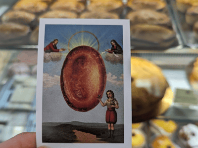 Carte représentant le Santo Pasticciotto, entourée de délicieuses pâtisseries à la Pâtisserie Natale.