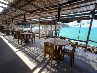 Welcoming terrace of Al Trabucco da Mimì with wooden tables, overlooking the turquoise sea and the coastal landscape.