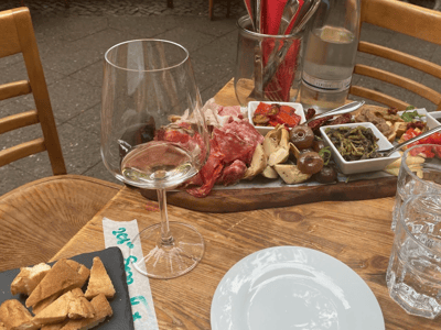 Planche de charcuterie élégante avec vin blanc, salades et crackers, dégustée sur une terrasse à Facciola.