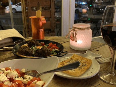 Delicious dinner with fresh dishes and a glass of red wine, cozy atmosphere at Rises Delicacies restaurant.