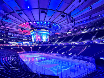 Atmosphere of Madison Square Garden, with the rink lit up and colorful lights, ready for a sports event.