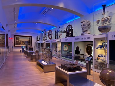 Exposition au New York Historical Society, montrant des artefacts divers et des sculptures liées à l'histoire de la ville.