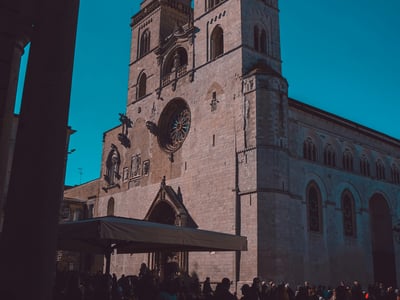 Imposing church in Altamura, with a lively crowd in the square, under a bright blue sky, illustrating the local heritage.