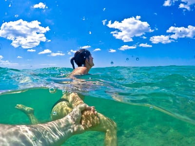 Woman swimming in the turquoise waters of Marina di Pescoluse, under a sunny and cloudy sky.