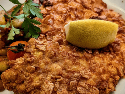 Escalope croustillante garnie de citron, accompagnée de légumes, servie à Treffpunkt Berlin. Parfait pour une pause gourmande.