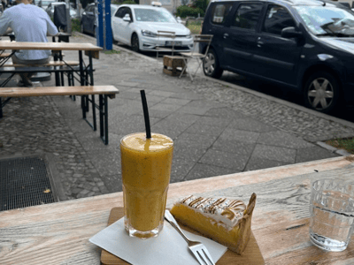 Smoothie frais et pâtisserie sur une table en bois, ambiance détendue au QG - Café français, avec vue sur la rue.