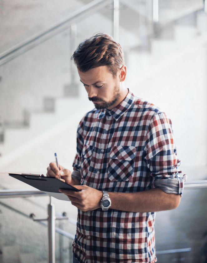 A man is writing on a clipboard in an office.