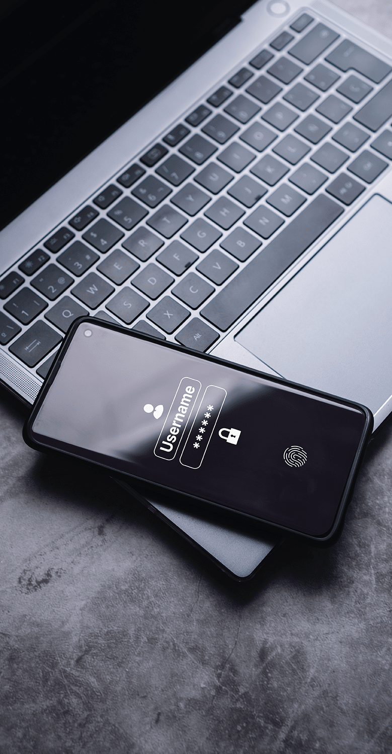 Enhancing Your WordPress Security A smartphone displaying a login screen with username and password fields rests on a laptop keyboard. The phone screen also shows fingerprint authentication.