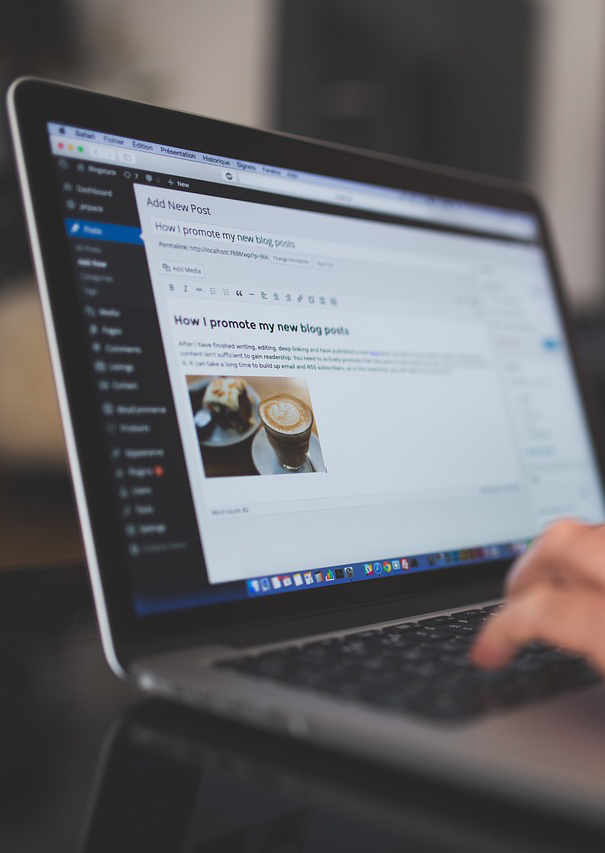 Person typing a blog post titled "How I promote my new blog posts" on a WordPress editor displayed on a laptop screen, highlighting the role of web hosting technology in boosting visibility and performance.