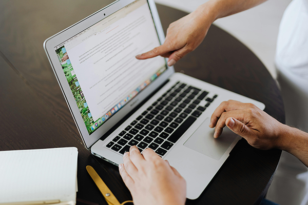 Break Up Long Content When Appropriate Two people work at a laptop; one types while the other points at text on the screen. A notebook and pen lie on the table beside them.