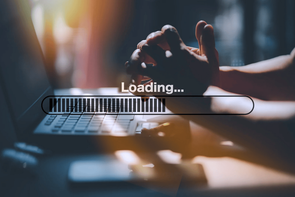 DNS Issues Can Undermine an Otherwise Well-Built Website A person sits at a laptop with hands clasped, while a digital loading bar with the word "Loading..." is displayed over the image.