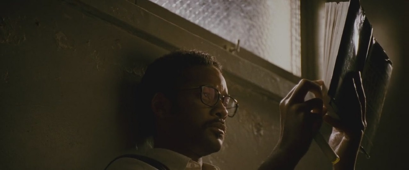 Chris Gardner reading a book in the light coming from a small window in the movie The Pursuit of Happyness.