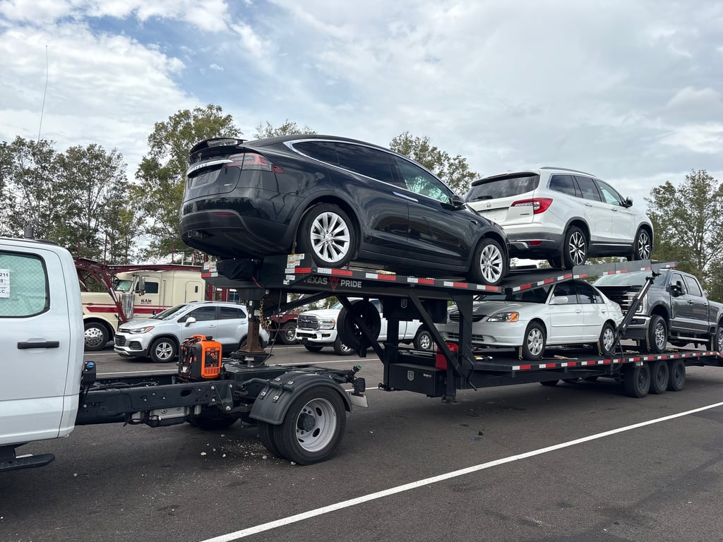 Tesla Model X on the top deck of a fully loaded Velocity Logistics Texas Pride car hauler
