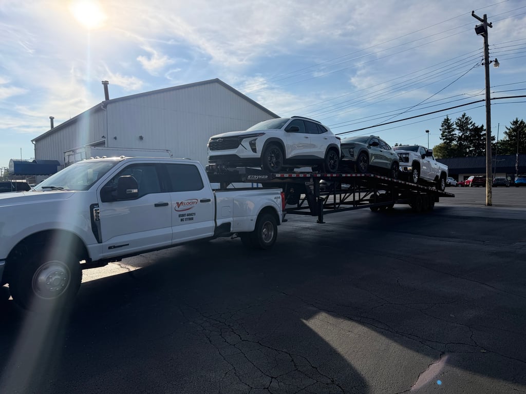 Velocity Logistics branded F-350 hitched to a loaded Stryker wedge carrier at sunrise