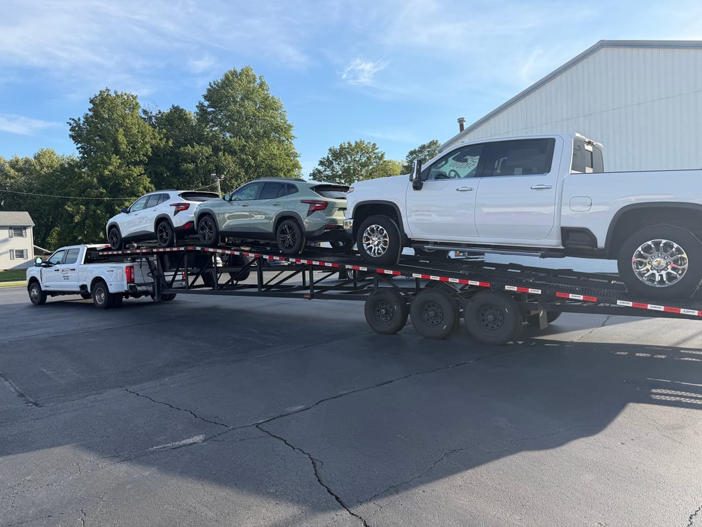 Velocity Logistics truck towing a wedge carrier loaded with a Chevrolet Silverado HD and two crossovers