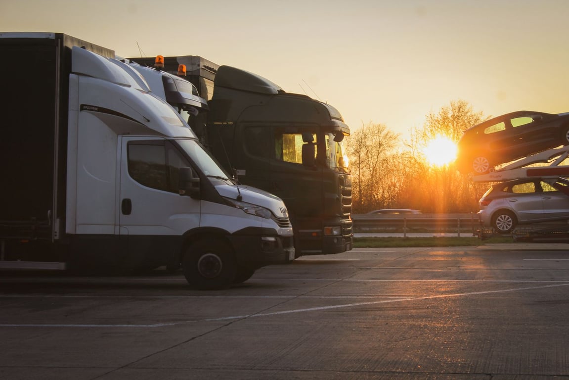 Trucks and a car transporter parked at sunset