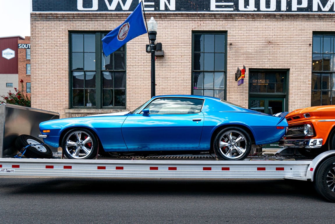 A blue classic car secured on a trailer