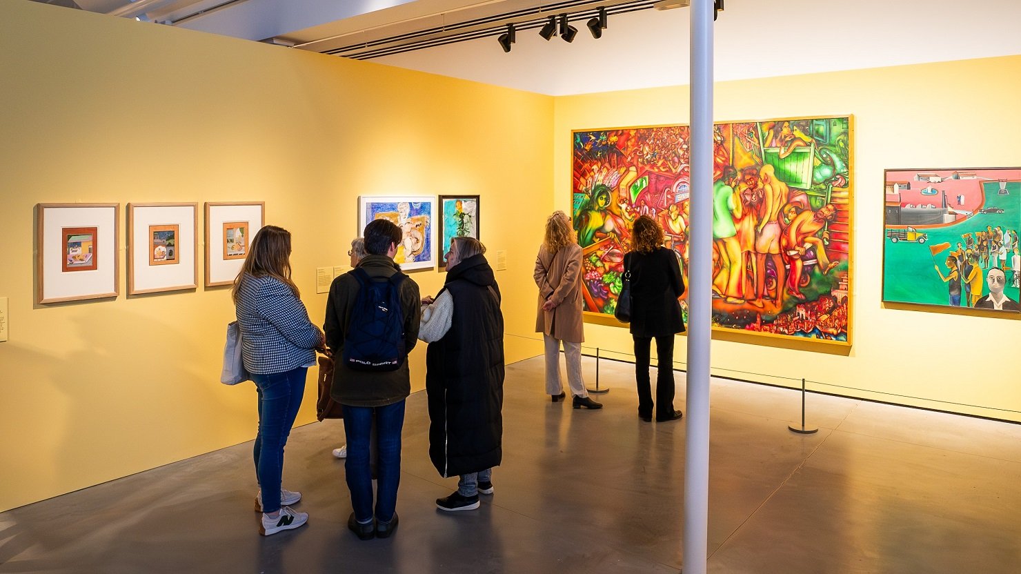 A small group of people look at an art exhibition in a gallery