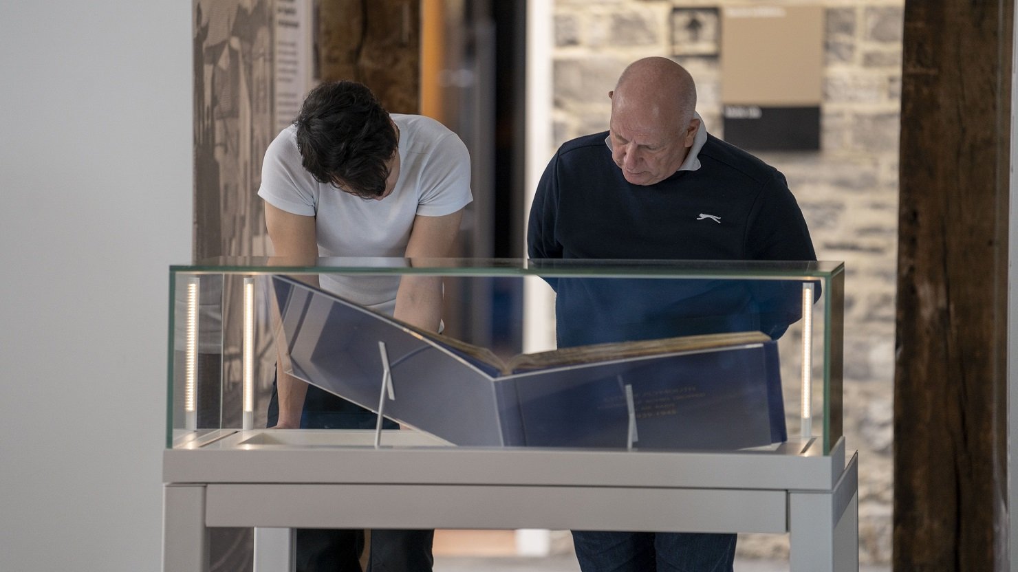 Two men look at the Bomb Book in The Box Plymouth's Active Archives gallery