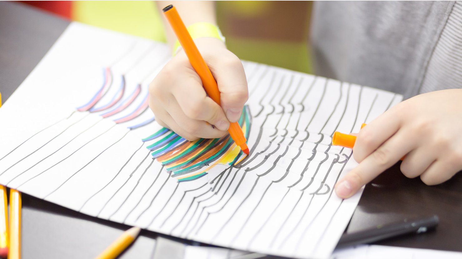 A child colours in a picture with felt pens