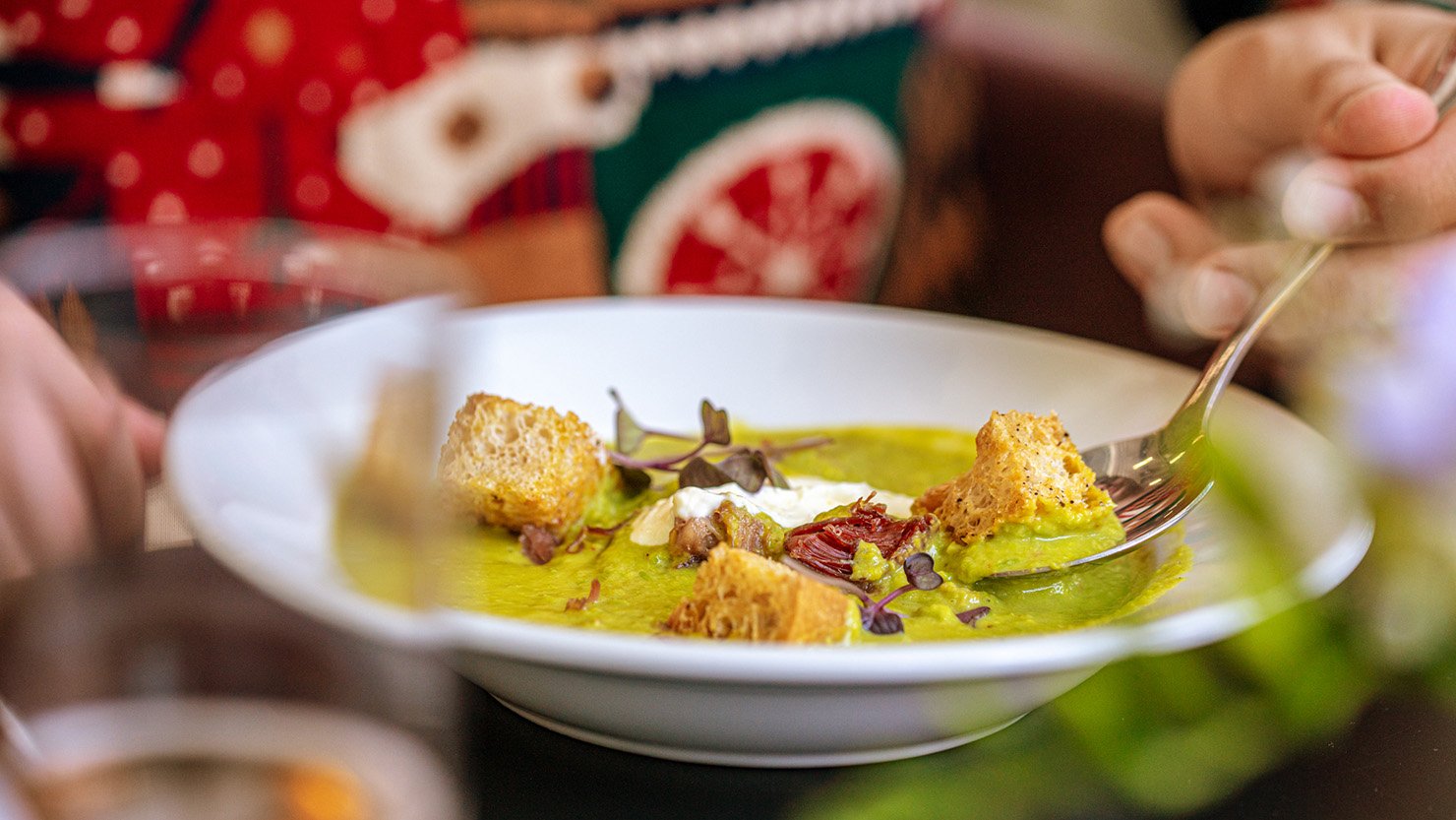 Closeup of someone wearing a Christmas jumper and eating soup