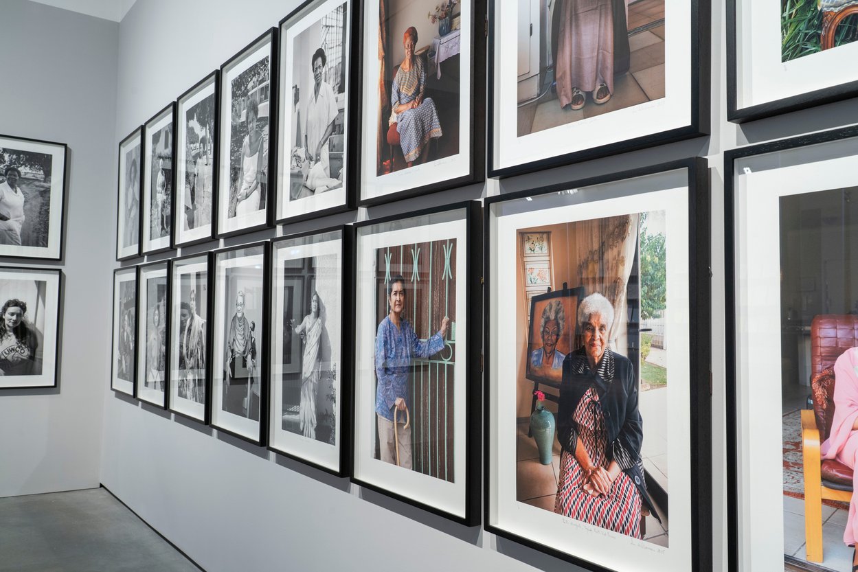 Photograph showing a photographic female portraits on display, with black and white to the left and colour photos to the right