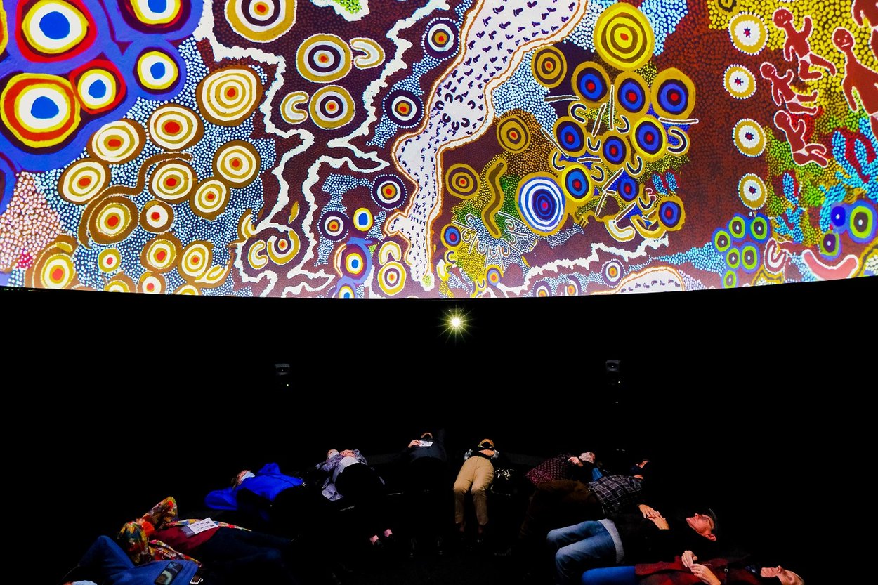 People watch a projection on the ceiling. Image © Getty.