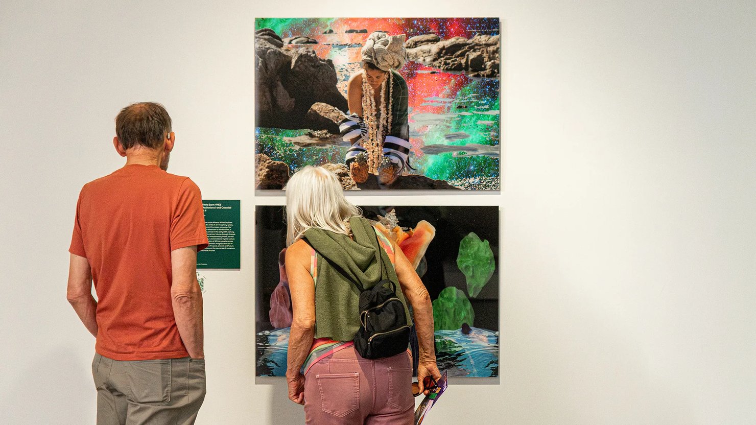 Two people looking at large prints on a gallery wall