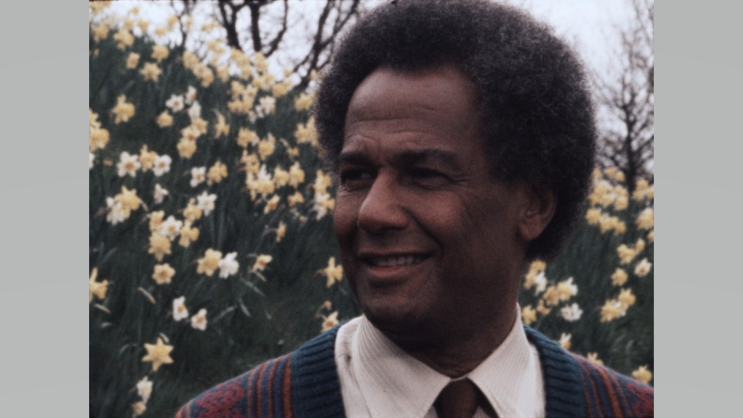Colour film still showing head and shoulders of actor and poet Cy Grant