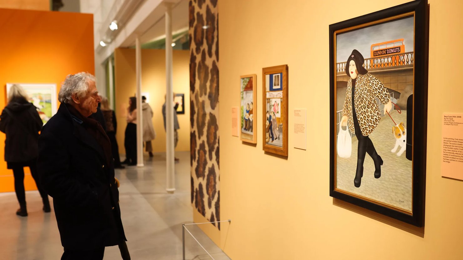 Photograph showing a man looking at a Beryl Cook painting of a woman wearing a leopard print coat