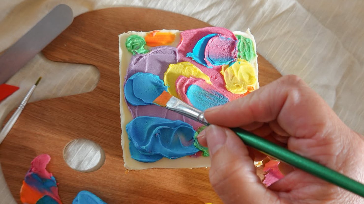 A person decorating a cake in colourful icing