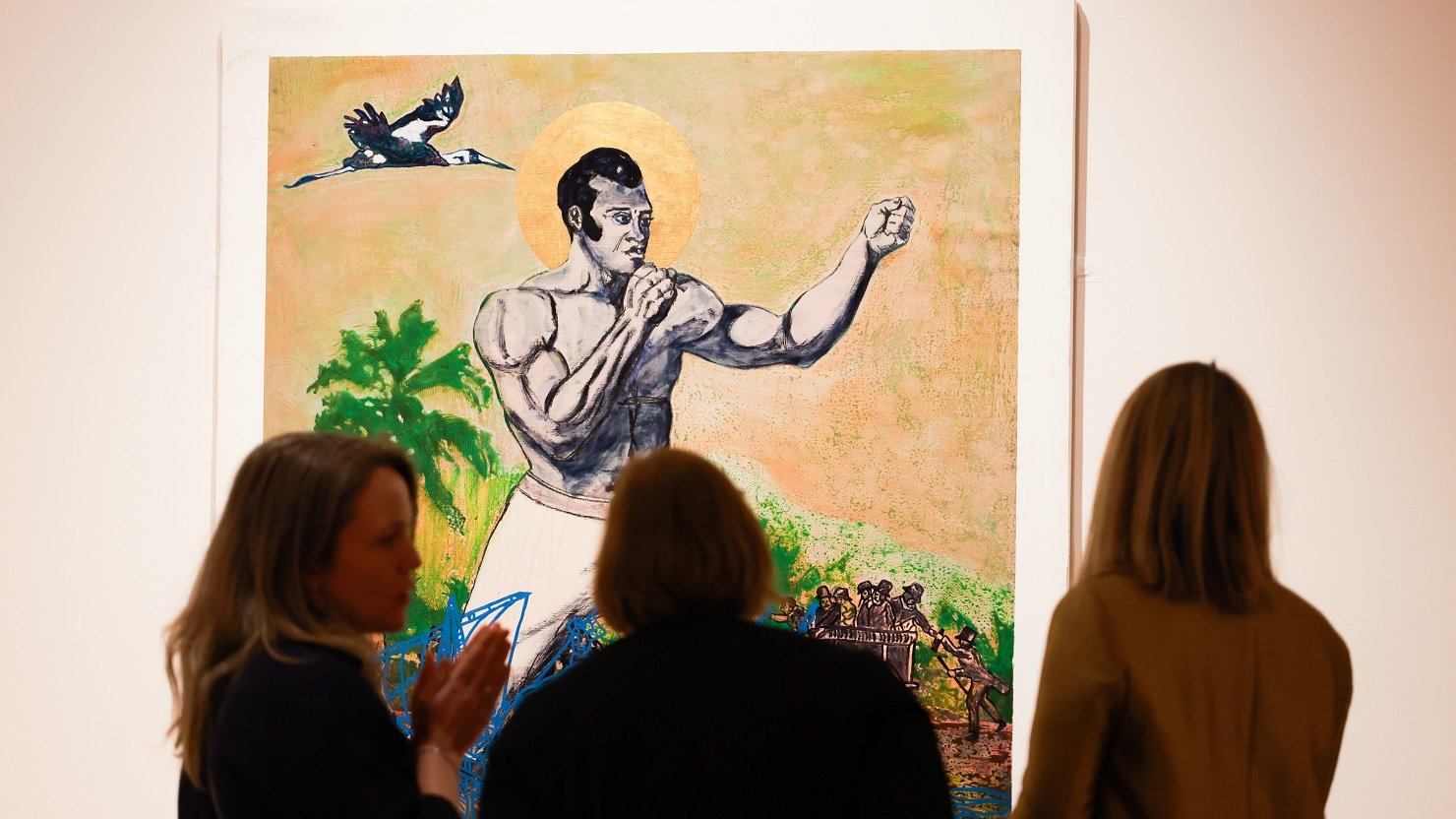 Three females discuss a painting hanging on a wall in a gallery