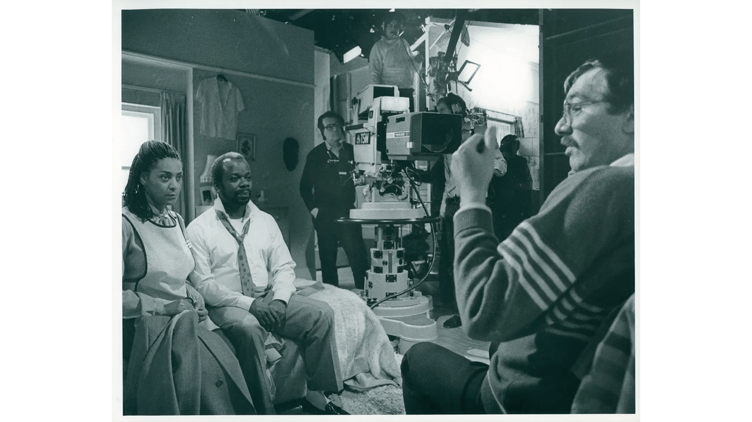 Photograph showing a tv programme being filmed, with crew and actors in a studio