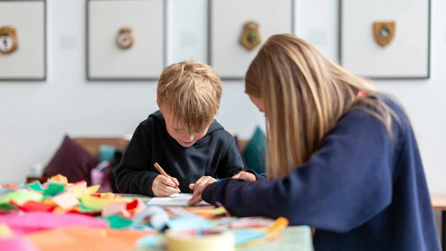 A boy and woman sitting at a table while they undertake a craft activity in The Box Plymouth's Explore More area