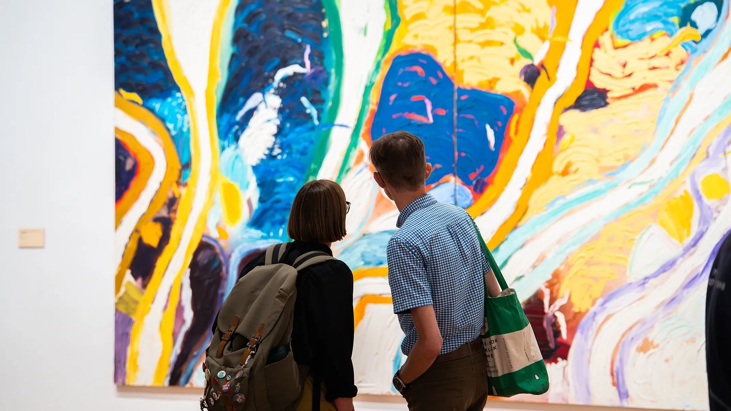 Photograph showing two people looking at a large abstract work from a distance