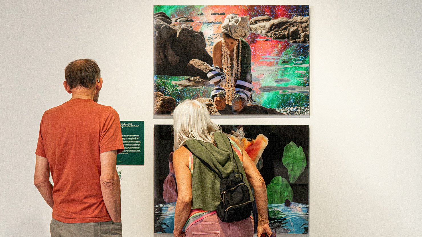 Photograph showing two people looking at large artworks with vibrant colours