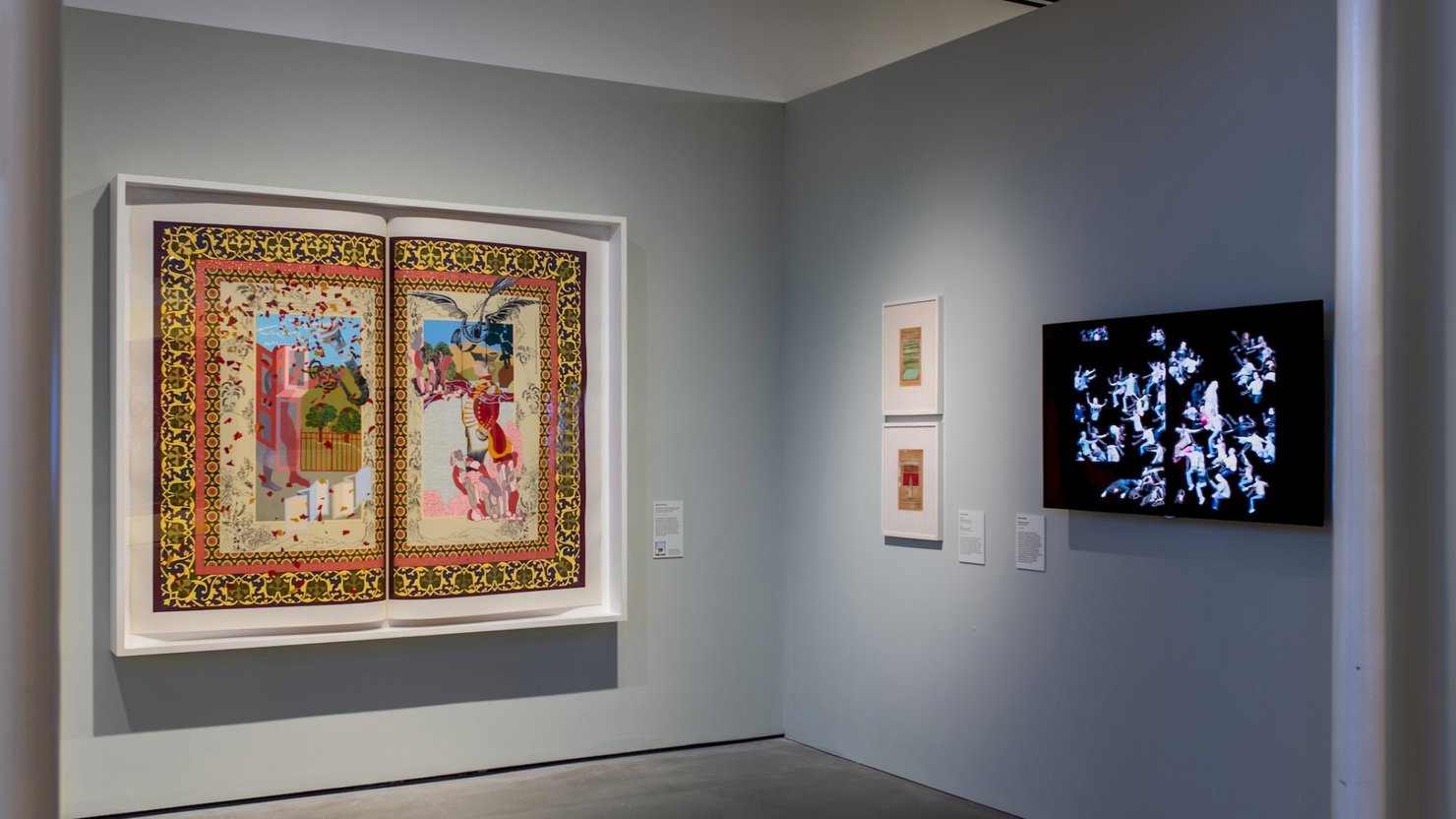 Photograph of a gallery showing a large artwork appearing like an open book with other smaller artworks on display.