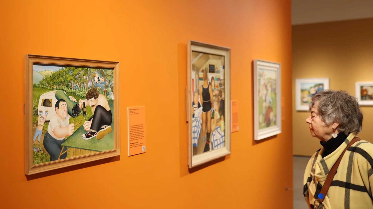 Photograph showing a lady looking at a painting of Beryl Cook's family