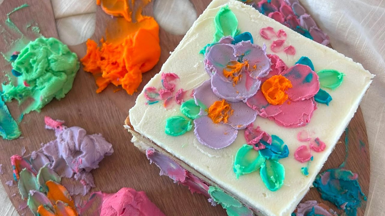 A person decorating a cake in colourful icing