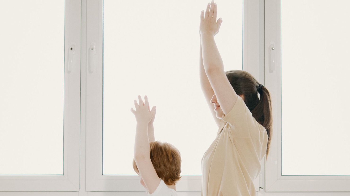 A woman and child dressed in white in a yoga pose