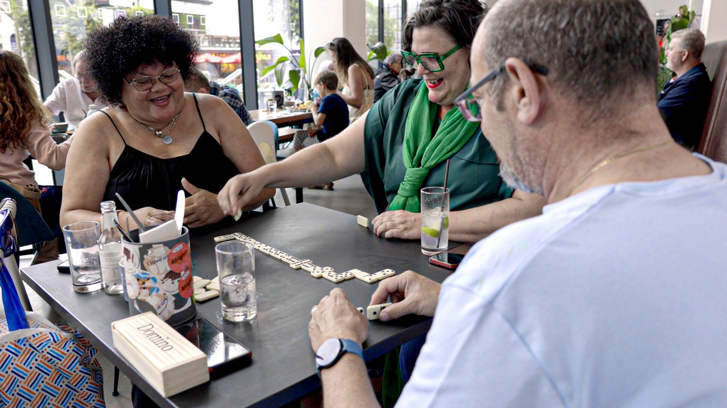 A group of three seated people playing dominoes