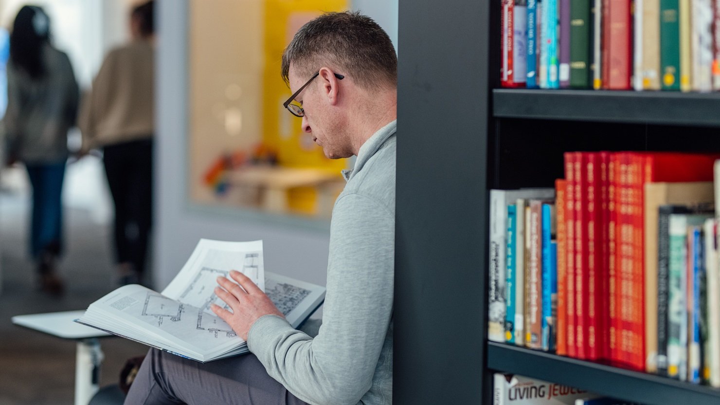A man reading a book in the Active Archives gallery at The Box