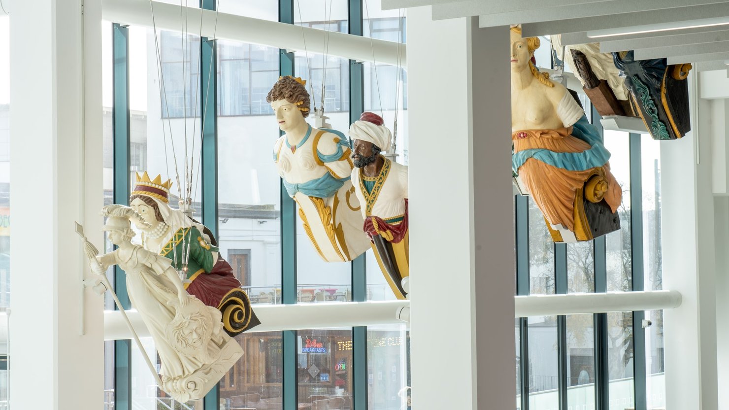 Photograph of ship's figureheads suspended from a ceiling