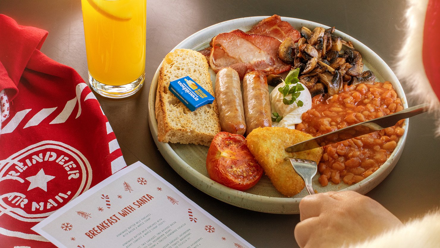 A Father Christmas seen just in shot eating a cooked breakfast