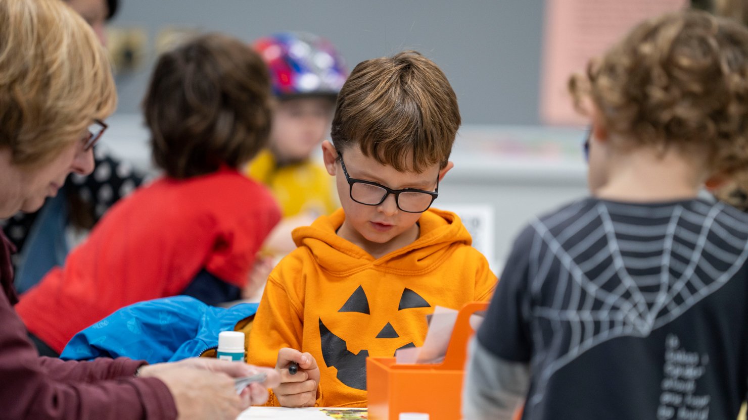 A young boy in an orange hoodie taking part in a craft workshop