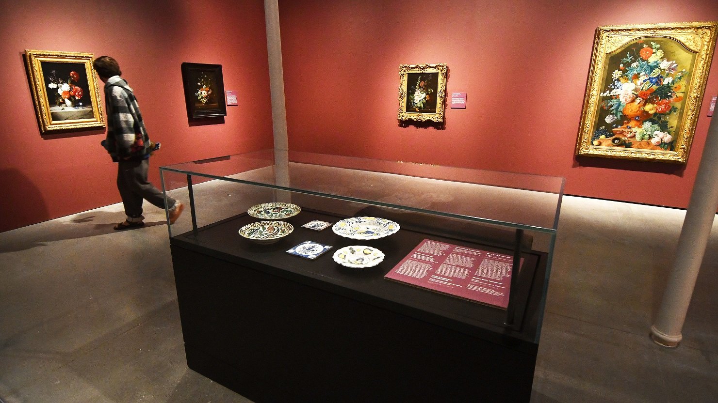 A visitor looks at an exhibition of Dutch flower paintings