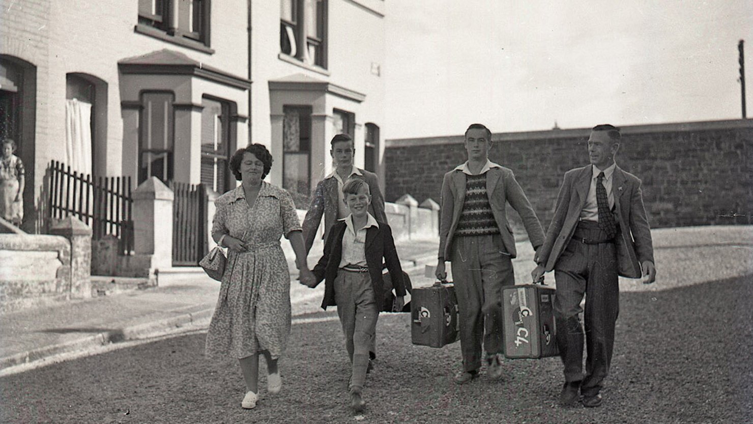 A woman, man and three sons walking with suitcases
