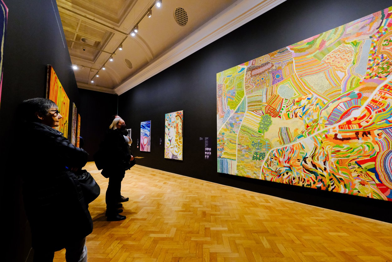 Visitors looking at a large bright painting in an art gallery