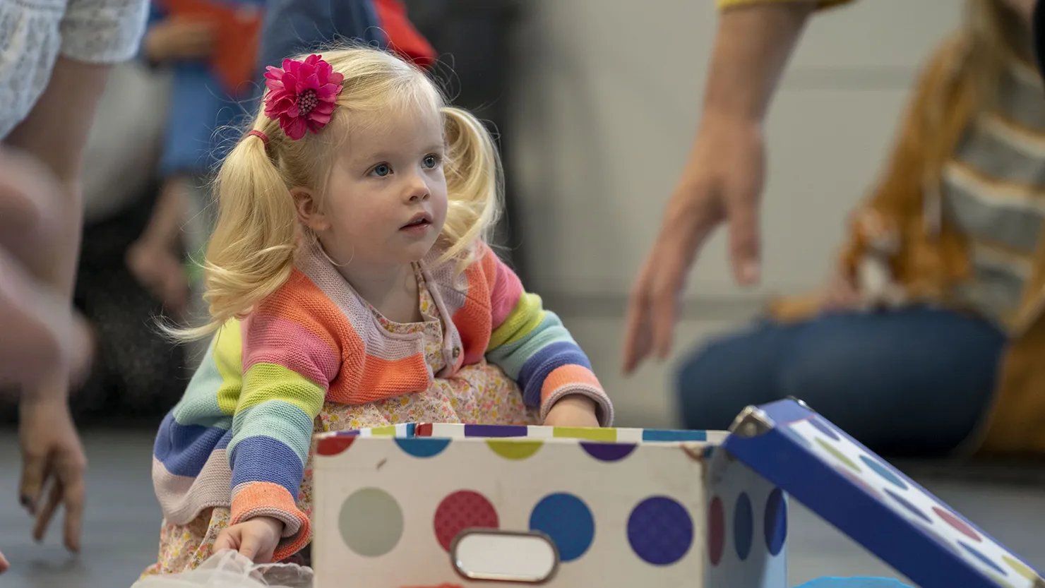 A young girl opening a box in a sensory workshop for toddlers and preschoolers